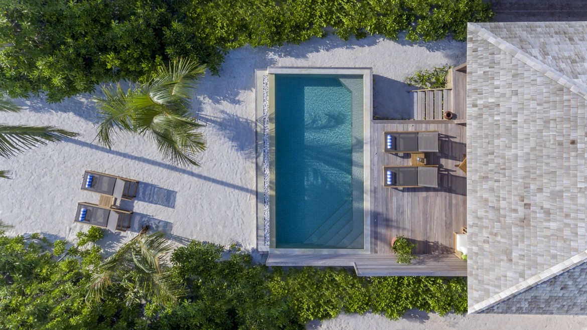 Private pool and lounge chairs surrounded by greenery at Hurawalhi Island Resort